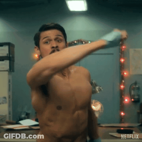 A Shirtless Man Is Standing In Front Of A Mirror And Holding A Hammer . GIF