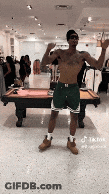 A Shirtless Man Is Standing In Front Of A Pool Table In A Store GIF