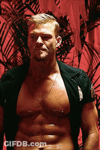 A Shirtless Man Is Standing In Front Of A Red Wall With A Palm Tree In The Background GIF