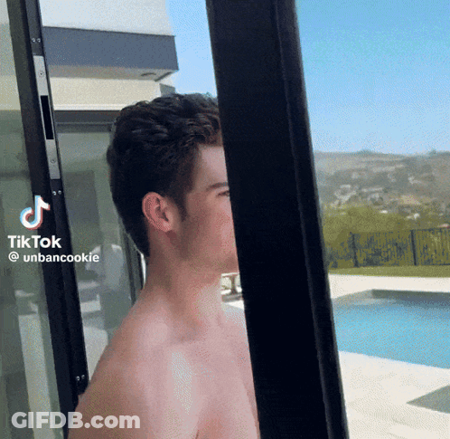 A Shirtless Man Is Standing In Front Of A Sliding Glass Door With Tiktok Written On The Bottom Right Corner GIF