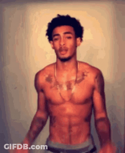 A Shirtless Man Is Standing In Front Of A Wall . GIF