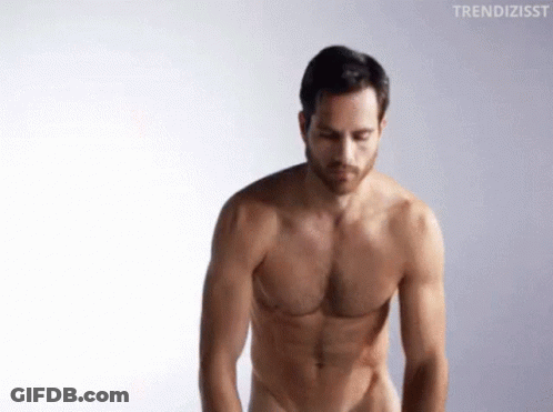 A Shirtless Man Is Standing In Front Of A White Background And Looking Down . GIF