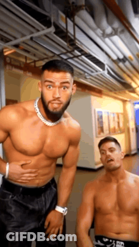 A Shirtless Man Is Standing Next To A Shirtless Man In A Hallway . GIF