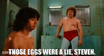 A Shirtless Man Is Standing Next To A Shirtless Wrestler In A Bathroom . GIF