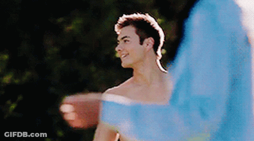 A Shirtless Man Is Standing Next To Another Shirtless Man In A Blue Jacket GIF