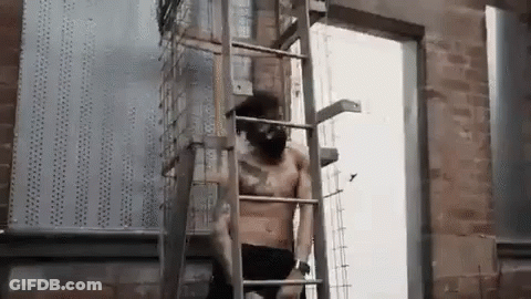 A Shirtless Man Is Standing On A Ladder . GIF