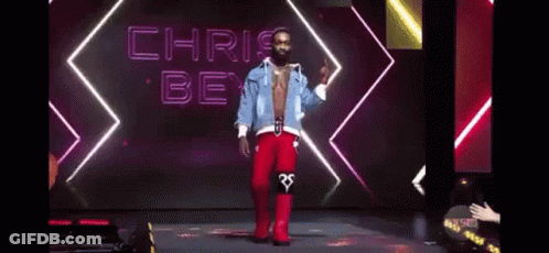 A Shirtless Man Is Standing On A Stage With His Tongue Out . GIF