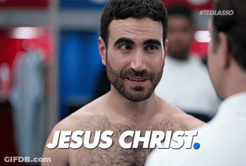A Shirtless Man Is Talking To Another Shirtless Man With The Words Jesus Christ Written On His Chest GIF