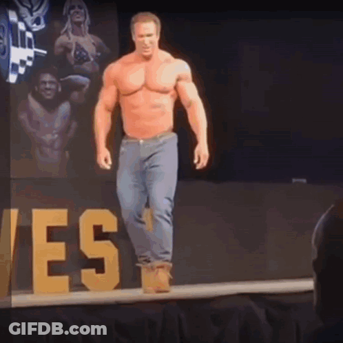 A Shirtless Man Is Walking Down A Stage With A Sign That Says Yes In The Background GIF