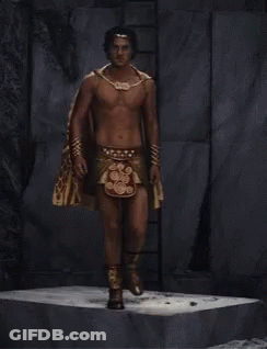 A Shirtless Man Is Wearing A Cape And A Necklace GIF