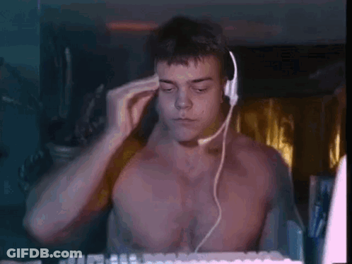 A Shirtless Man Is Wearing Headphones And A Headset While Sitting In Front Of A Computer Keyboard . GIF