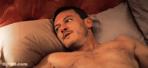 A Shirtless Man Laying On A Bed Looking Up GIF