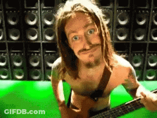 A Shirtless Man Playing A Guitar In Front Of Speakers GIF
