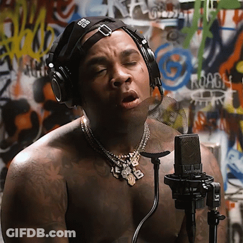 A Shirtless Man Singing Into A Microphone With Headphones On GIF
