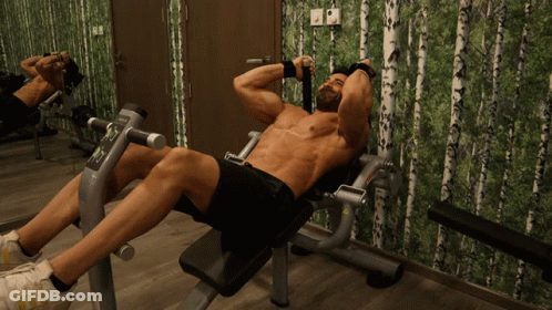 A Shirtless Man Sits On A Bench In Front Of A Mirror GIF