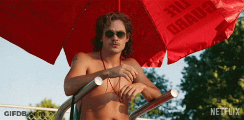 A Shirtless Man Sitting Under A Red Umbrella That Says Netflix On It GIF