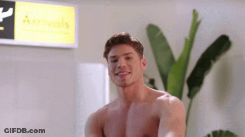 A Shirtless Man Smiles In Front Of A Sign That Says Arrivals GIF