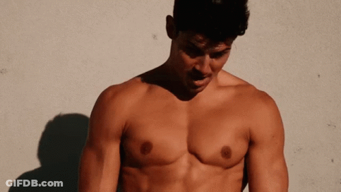 A Shirtless Man Standing In Front Of A Wall GIF