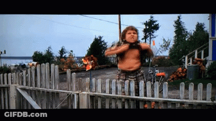 A Shirtless Man Standing In Front Of A Wooden Fence GIF