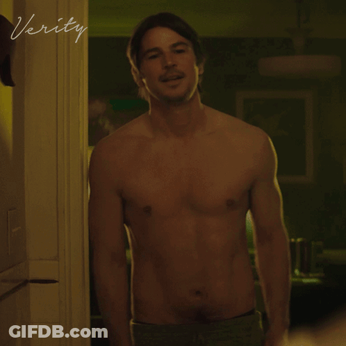 A Shirtless Man Stands In A Doorway With The Word Verity Written On The Wall GIF