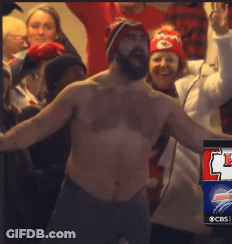 A Shirtless Man Stands In Front Of A Crowd Of People With A Cbs Advertisement In The Corner GIF