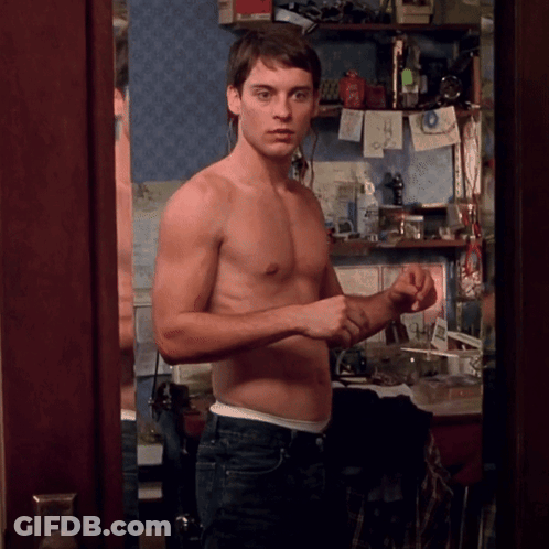A Shirtless Man Stands In Front Of A Mirror In A Room GIF