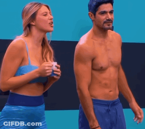 A Shirtless Man Stands Next To A Woman In A Blue Bra GIF