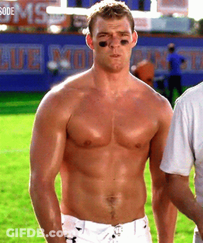 A Shirtless Man Stands On A Field In Front Of A Sign That Says ' Blue Monsters ' GIF