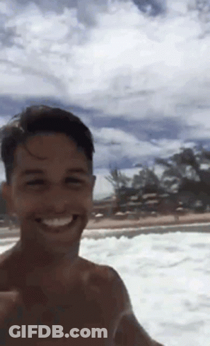A Shirtless Man Taking A Selfie In The Ocean GIF