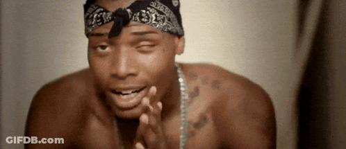 A Shirtless Man Wearing A Bandana And A Chain Is Praying . GIF