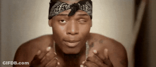 A Shirtless Man Wearing A Bandana And A Necklace Is Making A Face . GIF