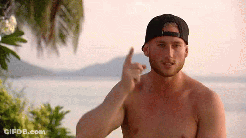 A Shirtless Man Wearing A Baseball Cap Is Pointing At Something GIF