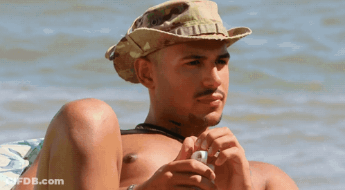 A Shirtless Man Wearing A Cowboy Hat Is Looking At His Phone GIF