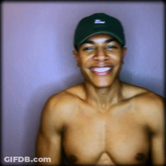 A Shirtless Man Wearing A Green Hat With The Letter T On It Smiles GIF
