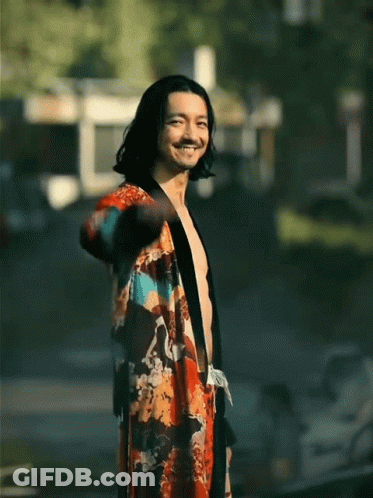 A Shirtless Man Wearing A Kimono Is Smiling And Waving GIF