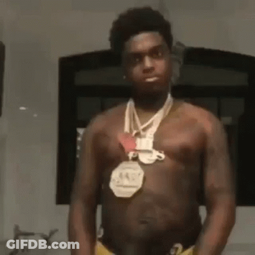 A Shirtless Man Wearing A Medal Around His Neck . GIF