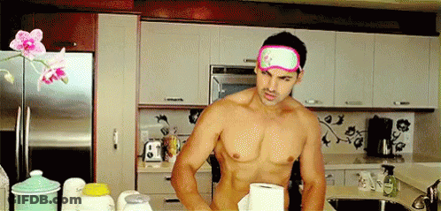 A Shirtless Man Wearing A Pink Eye Mask Is Standing In A Kitchen . GIF