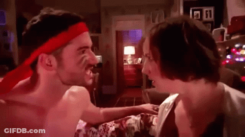 A Shirtless Man Wearing A Red Headband Is Fighting A Woman In A Bedroom . GIF