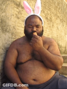 A Shirtless Man Wearing Bunny Ears Is Eating An Ice Cream GIF