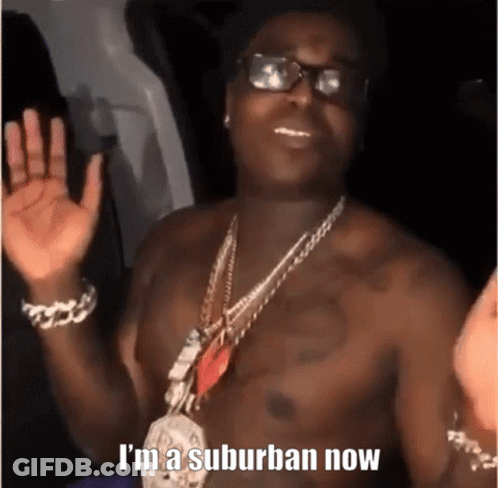 A Shirtless Man Wearing Glasses And A Necklace With The Words `` I 'M A Suburban Now '' On It . GIF