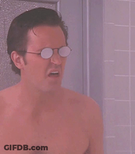 A Shirtless Man Wearing Glasses Is Taking A Shower In A Bathroom GIF