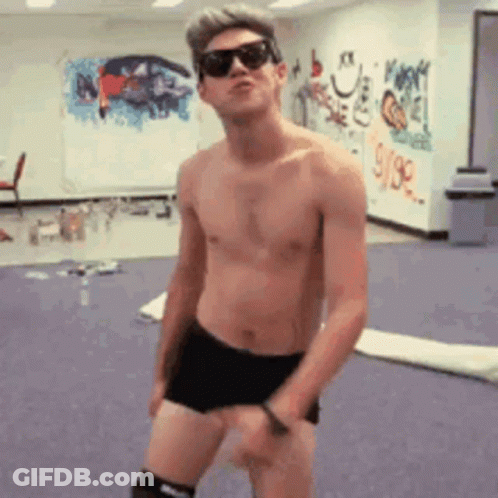 A Shirtless Man Wearing Sunglasses Is Dancing In A Room With Graffiti On The Wall GIF