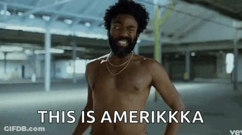 A Shirtless Man With A Beard And A Necklace Says This Is Amerikkka GIF