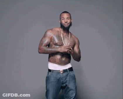 A Shirtless Man With A Beard And Tattoos Is Dancing . GIF