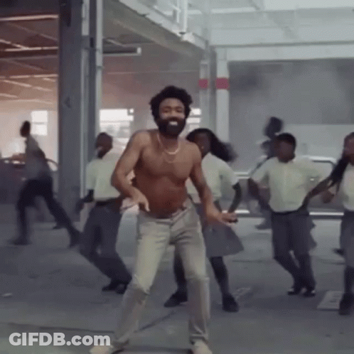 A Shirtless Man With A Beard Is Dancing With A Group Of People . GIF