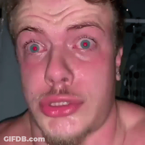 A Shirtless Man With A Beard Is Making A Funny Face With His Mouth Open And His Eyes Wide Open . GIF