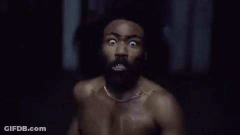 A Shirtless Man With A Beard Is Running In A Dark Room With His Eyes Wide Open . GIF