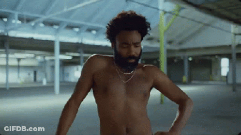 A Shirtless Man With A Beard Is Standing In An Empty Warehouse GIF