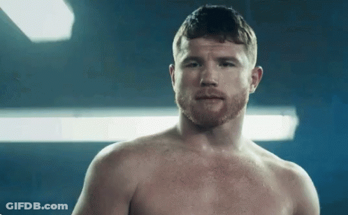 A Shirtless Man With A Beard Is Standing In Front Of A Blue Background . GIF