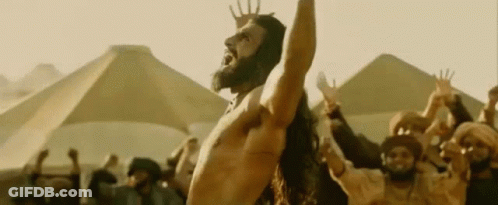 A Shirtless Man With A Beard Is Standing In Front Of A Crowd Of People . GIF